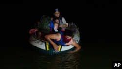 FILE - A smuggler takes migrants, mostly from Central American countries, on a small inflatable raft towards U.S. soil in Roma, Texas, March 30, 2021. 