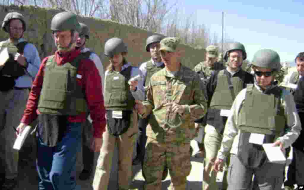 Colonel David Flynn walks toward Tabin Village in Kandahar Province with reporters who are covering Secretary Gates' visit, March 8, 2011