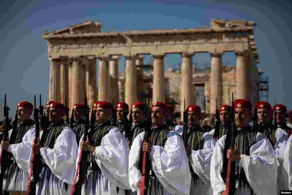 Greek Presidential Guards, known as Evzones, present arms during a ceremony atop the Acropolis hill in Athens, Oct. 12, 2019, for the 75th anniversary of the Liberation of Athens from the Nazi occupation.