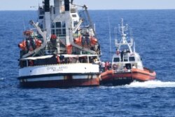 An Italian Coast Guard boat, right, approaches the Spanish humanitarian rescue ship Open Arms, off the Sicilian island of Lampedusa, southern Italy, Aug. 20, 2019.