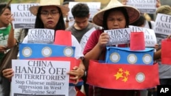 FILE - Filipino student activists hold mock Chinese ships to protest recent island-building and alleged militarization by China off the disputed Spratlys group of islands in the South China Sea, during a rally in Manila, Philippines, March 3, 2016.