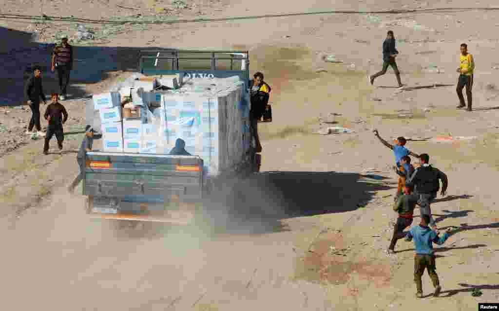 Palestinians rush to take aid from a truck, following a ceasefire between Israel and Hamas, in Rafah in the southern Gaza Strip.