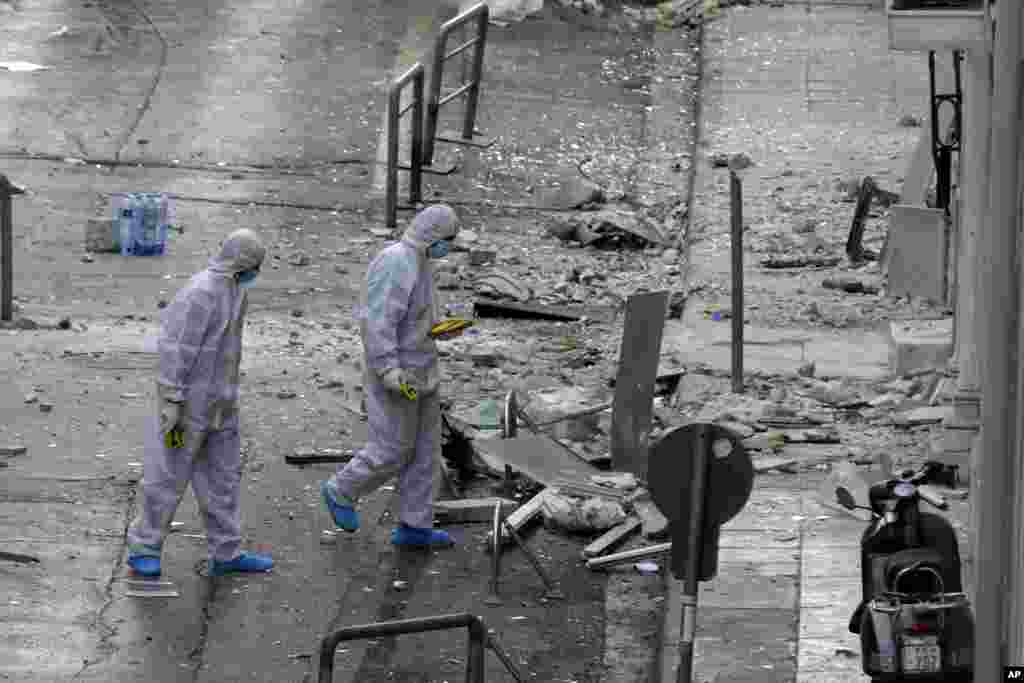 Police forensic experts search a street for evidence after a bomb explosion outside the Federation of Greek Enterprises in central Athens.