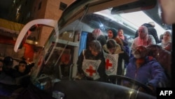 Palestinian prisoners, back, wait to disembark from a Red Cross bus upon their arrival in the occupied West Bank town of Beitunia, on the outskirts of Ramallah, following their release by Israel in the early hours of January 20, 2025.