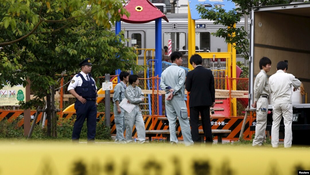 Workers of Tokyo's Toshima ward office and police officers are seen in front of the playground equipment where high levels of radiation were detected at a park in Toshima ward, Tokyo, April 24, 2015. 