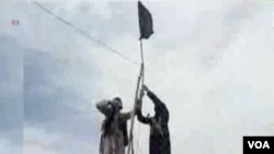 FILE - Members of Islamic State-Khorasan raise a flag in a tribal region of Afghanistan, Nov. 2, 2015. 