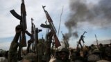 FILE - Rebel fighters hold up their rifles as they walk in front of a bushfire in a rebel-controlled territory in Upper Nile state, South Sudan Feb. 13, 2014. 