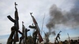 FILE - Rebel fighters hold up their rifles as they walk in front of a bushfire in a rebel-controlled territory in Upper Nile state, South Sudan, Feb. 13, 2014. 