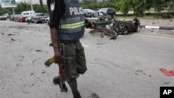 Un policier nigérian passant à côté de l'épave d'une voiture brûlée dans l'une des explosions d'Abuja, 1er octobre 2010.