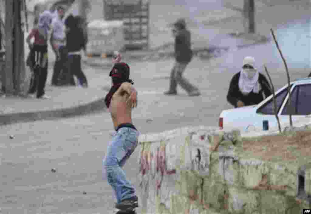 A Palestinian youth throws stones at Israeli riot police, not seen, during a protest against Jewish settlements in the east Jerusalem neighborhood of Silwan, Monday, Dec. 27, 2010. Tensions regularly run high in Silwan, where a small group of Israeli sett