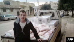 Foto sin fecha de Peter Kassig arrimado a un camión con provisiones en un lugar desconocido.