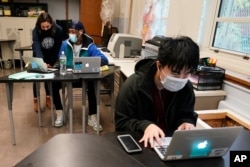 FILE - Students navigate an online lesson with the help of an instructor, at West Brooklyn Community High School in New York City, Oct. 29, 2020.