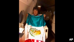 This photo released by by Mexico's Foreign Minister Marcelo Ebrard shows Bolivia's former President Evo Morales holding a Mexican flag aboard a Mexican Air Force aircraft, Nov. 11, 2019. 