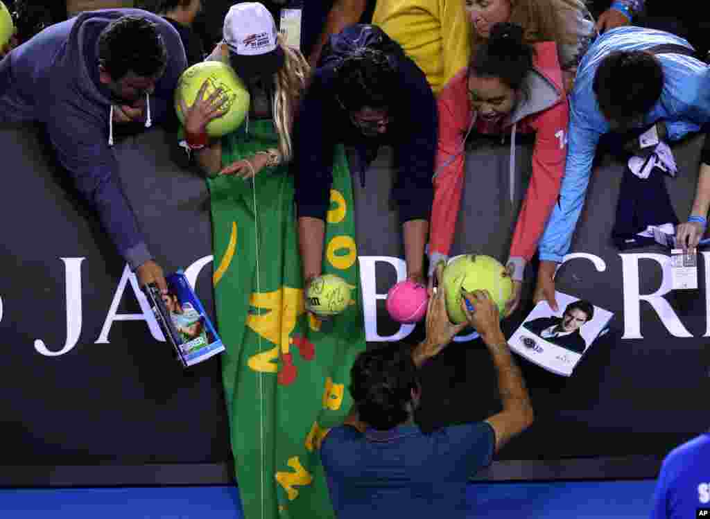 Roger Federer of Switzerland signs autographs for fans after defeating Andy Murray of Britain in the quarterfinal at the Australian Open tennis championship in Melbourne.