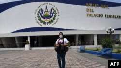  Menly Jazmin Cortez González, de 29 años, reportero gráfico, usa una máscara quirúrgica mientras posa fuera del salón azul de la Asamblea Legislativa en San Salvador el 24 de abril de 2020