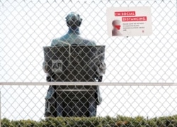 In this May 7, 2020 photo, a statue of Abraham Lincoln, a traditional gathering spot for photos of graduates at the University of Wisconsin-Madison in Madison, Wis., remains fenced-off to visitors.