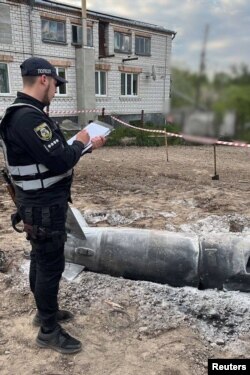 Police officer inspects a cruise missile shot down during Russian missile strike in the backyard of a private house in Kyiv region