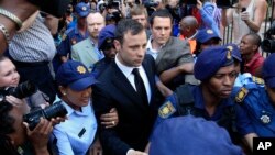Escoltado por la policía Oscar Pistorius abandona la corte en Pretoria luego de escuchar los cargos por la muerte de su novia.