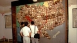 Visitors to Toul Sleng, officially known as S-21 prison look at a wall of sculls and bones made into a map of Cambodia.