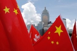 FILE - Buildings are seen above Hong Kong and Chinese flags, as pro-Beijing activists celebrate after China's parliament passes a national security law for Hong Kong, in Hong Kong.