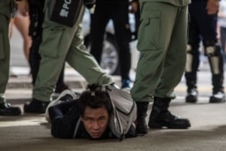 FILE - Riot police detain a man as they clear protesters taking part in a rally against a new national security law in Hong Kong, July 1, 2020.