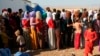 FILE - Displaced members of the Yazidi community line up for humanitarian aid at Nowruz camp, in Derike, Syria, Aug. 12, 2014. 