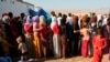 FILE - Warga Irak yang mengungsi dari komunitas Yazidi berkumpul untuk mendapatkan bantuan kemanusiaan di kamp Nowruz, Derike, Suriah, 12 Agustus 2014. (Khalid Mohammed, Arsip/AP)