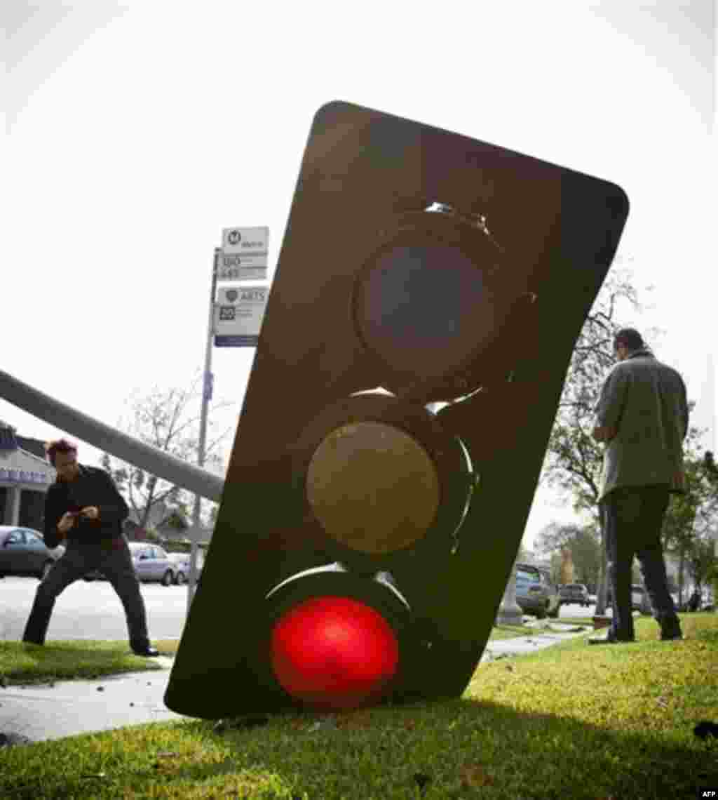 Pedestrians photograph a fallen traffic signal caused by high Santa Ana winds at the corner of Lake Avenue and Claremont Street, Thursday, Dec. 1, 2011, in Pasadena, Calif. Some of the fiercest winds in years slam California and move across the West, wit