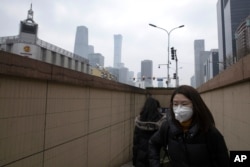 Residents walk out of a subway station in Beijing, March 9, 2020. With almost no new COVID-19 cases being reported in Beijing, workers are slowly returning to their offices with masks on and disinfectant in hand.