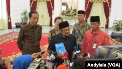 Usai bertemu Presiden Jokowi, Presiden ketiga RI BJ Habibie memperlihatkan buku biografinya berjudul "RUDY" kepada wartawan di Istana Merdeka, Jakarta, 13 Oktober 2015 (Foto: VOA/Andylala)