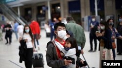 FILE - People wearing protective face masks walk through Waterloo Station, amid the coronavirus pandemic, in London, Britain, July 4, 2021. 