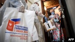 A woman wearing a face mask — a measure against the spread of the coronavirus disease — stands by the door of her flat as she prepares to cast her ballot in a mobile ballot box during a nationwide vote on constitutional reforms in Moscow, July 1, 2020.