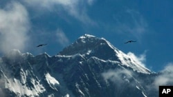 FILE - In this May 27, 2019, file photo, birds fly as Mount Everest is seen from Namche Bajar, Solukhumbu district, Nepal. 