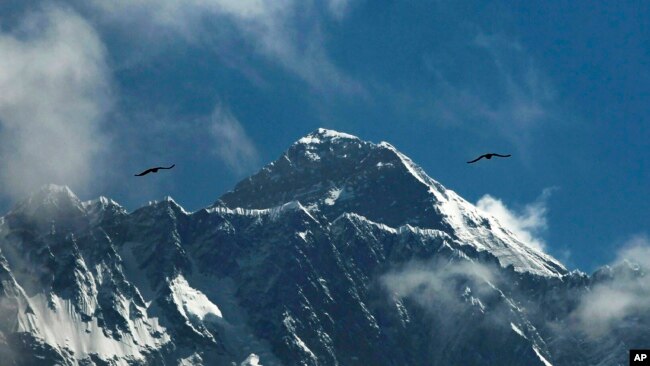 FILE - In this May 27, 2019, file photo, birds fly as Mount Everest is seen from Namche Bajar, Solukhumbu district, Nepal.