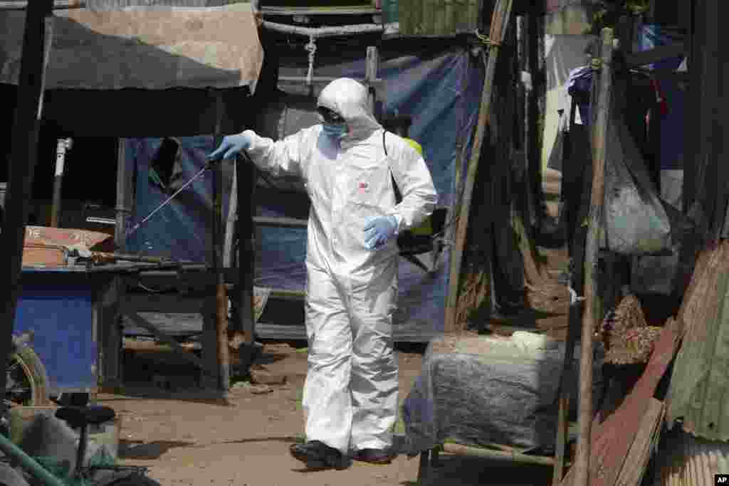 A member of the non-profit Cambodian Children&#39;s Fund sprays disinfectant to help curb the spread of the new coronavirus in the slum neighborhood of Stung Meanchey in southern Phnom Penh, Cambodia, on Tuesday, March 24, 2020. (AP Photo/Heng Sinith)