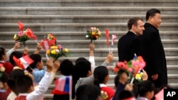 French President Emmanuel Macron, left, and Chinese President Xi Jinping react as schoolchildren wave Chinese and French flags during a welcome ceremony at the Great Hall of the People in Beijing, Nov. 6, 2019.
