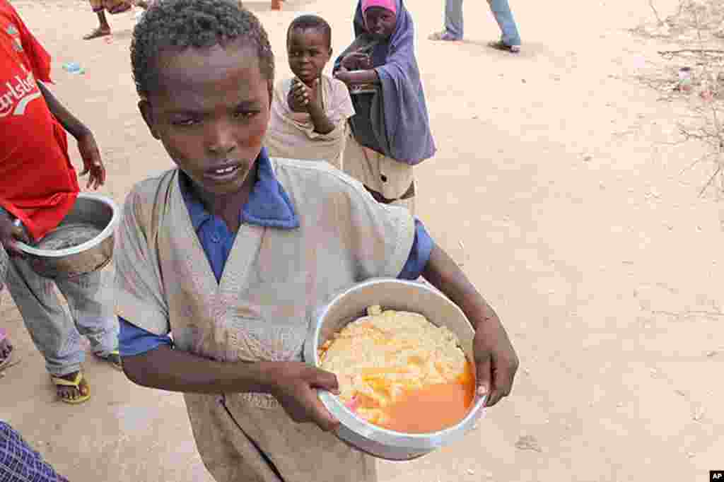 Boy with pot of gruel camp at Badbaado IDP camp in Mogadishu, Somalia. (VOA - P. Heinlein)