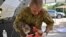 A member of the Australian Defence Force picks up an injured Koala after it was treated for burns at a makeshift field hospital at the Kangaroo Island Wildlife Park on Kangaroo Island.