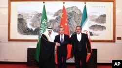 中共官媒新华社发布照片显示伊朗最高国家安全委员会秘书阿里·沙姆哈尼（右）在北京同沙特国务大臣、内阁成员和国家安全顾问穆萨伊德·本·穆罕默德·艾班握手，中间是中共中央外办主任王毅。（2023年3月11日）