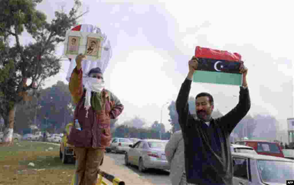 A resident, right, holds a pre-Gadhafi era national flag as he celebrates in Benghazi, Libya on Monday, Feb. 21, 2011. Libyan protesters celebrated in the streets of Benghazi on Monday, claiming control of the country's second largest city after bloody fi