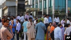 People stand outside their office building after a 6.2 earthquake is felt in Islamabad, Pakistan, Wednesday, May 9, 2018.