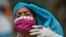 Una mujer con tapaboca y guantes desechables se ajusta el pañuelo en la cabeza mientras sale a caminar de hogar de ancianos en medio de la cuarentena por el coronavirus en Caracas, Venezuela.