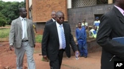 FILE: Elton Mangoma, center, Zimbabwe's Minster of Energy and Power Development outside the magistrates courts, accompanied by two unidentified police detectives in Harare, March, 11, 2011