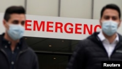 FILE - People walk past a hospital emergency entrance sign during the coronavirus pandemic in the Manhattan borough of New York City, Dec. 4, 2020. 
