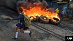 Une jeune écolière passe devant des barricades en feu à Kibera, Nairobi le 23 mai 2016.