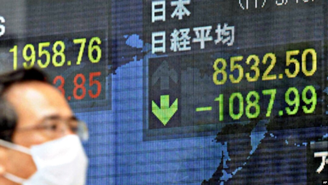 A man walks past a screen displaying stock prices in Tokyo, March 15, 2011