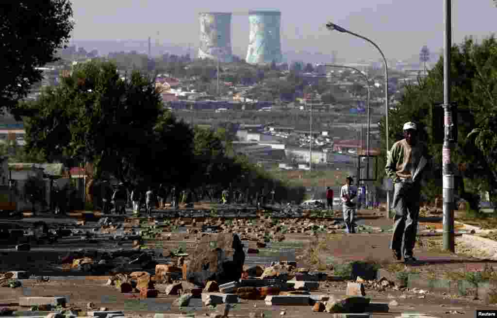 A man walks on a street filled with rocks and stones left behind by protesters who were dispersed by police in Soweto, South Africa. 