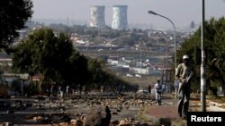 Un homme marche sur une rue jonchée de de pierres laissées par les manifestants dispersés par la police à Soweto, Afrique du Sud, 7 mai 2015. IMAGES REUTERS / Siphiwe Sibeko TPX DU JOUR