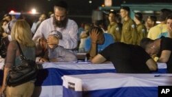 Relatives mourn over the coffins of people killed in a bombing in Bulgaria as the remains arrived back at an airport in Tel Aviv, Israel, Friday, July 20, 2012. A man carried out a deadly suicide attack on a bus full of Israeli vacationers on Wednesday i