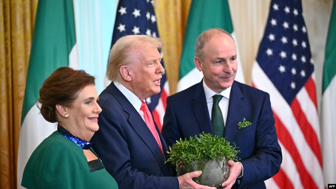 US President Donald Trump and Irish Prime Minister Micheal Martin (R) hold a bowl of shamrock alongside his wife Mary O'Shea (L) during a St. Patrick's Day Reception in the East Room of the White House in Washington, DC, on March 12, 2025. (Photo by Mande